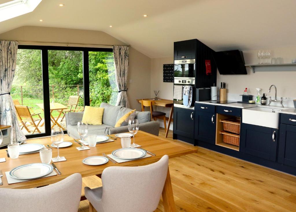 a kitchen and living room with a table and chairs at The Cabin at the Croft - Idyllic rural retreat perfect for couples and dogs in Leigh