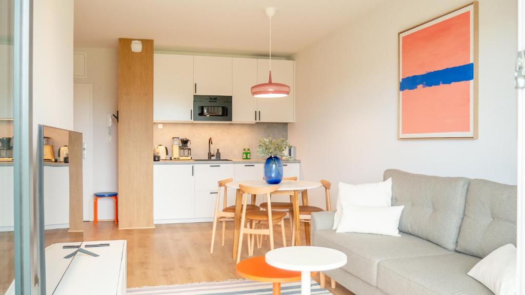 a living room and kitchen with a couch and a table at Apartament RAINBOW SurfingBird Dźwirzyno in Dźwirzyno