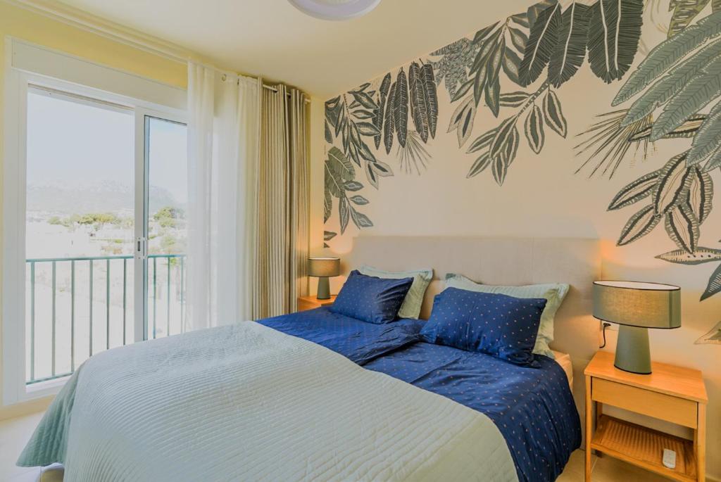een slaapkamer met een bed met blauwe lakens en een raam bij Apto. Estrella de Calpe in Calpe