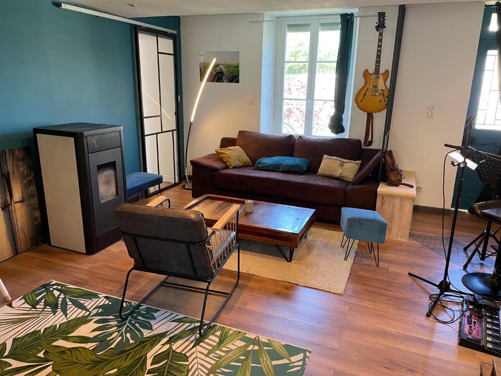 un salon avec un canapé et une guitare dans l'établissement Maison de ville Omaha Beach, à Le Molay-Littry