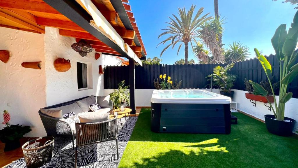 a backyard with a hot tub and a couch on a lawn at Oasis Beach Holiday Home with jacuzzi in Playa del Ingles