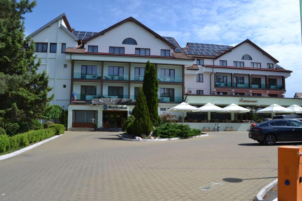 a large building with a car parked in a parking lot at Best Western Silva Hotel in Sibiu
