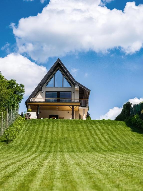 a house on top of a grassy hill at Franc Holiday House With a Spacious Terrace, Hot Tub And Sauna in Lopatinec