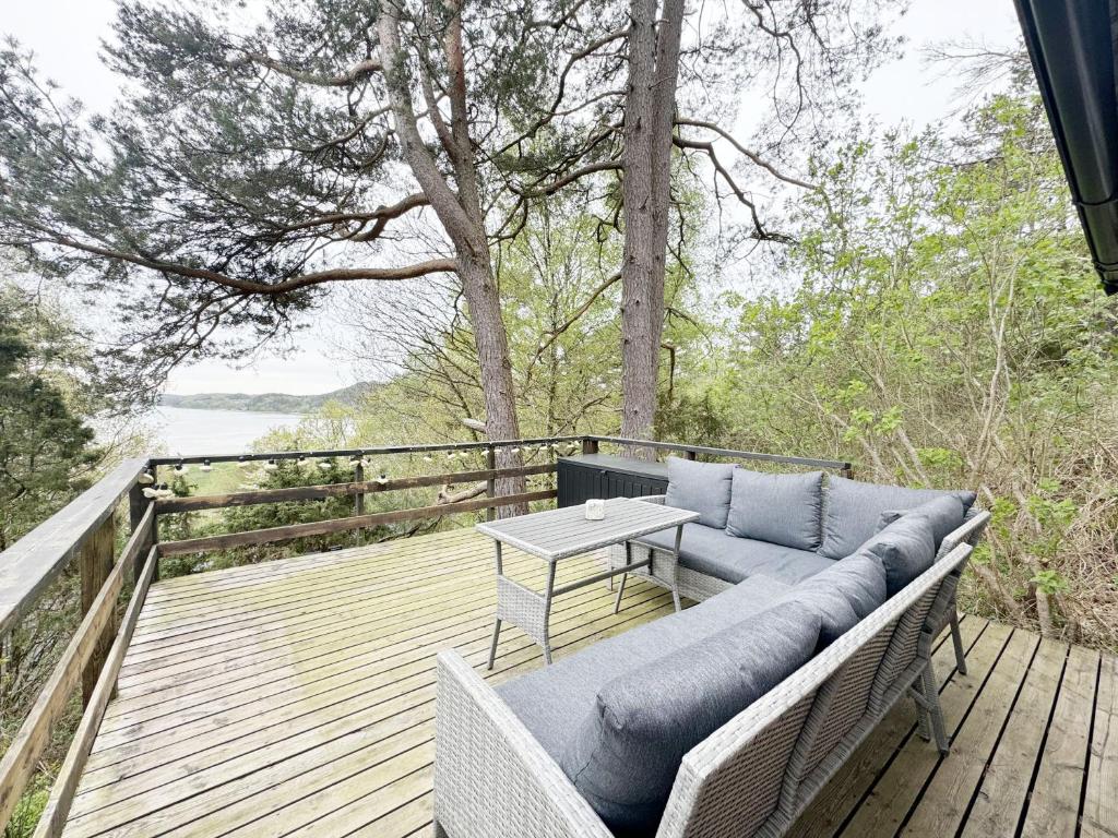 um pátio com um sofá e uma mesa num deque em Cozy cottage in a beautiful setting by the Abyfjorden-Brastad em Brastad