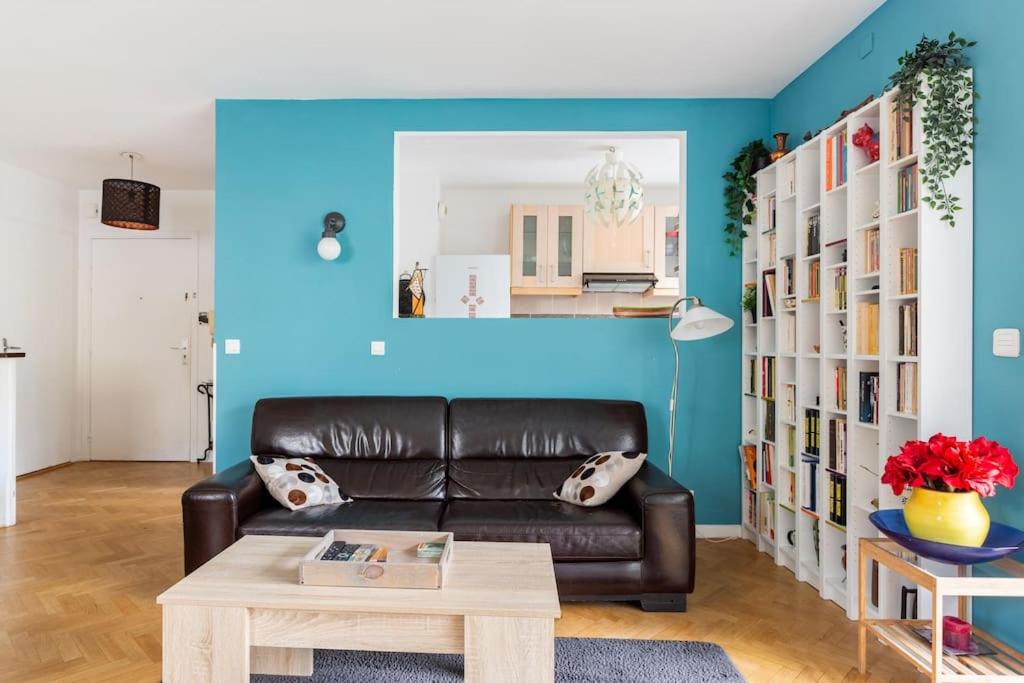 - un salon avec un canapé en cuir et un mur bleu dans l'établissement Bel appartement avec terrasse et parking gratuit, à Massy