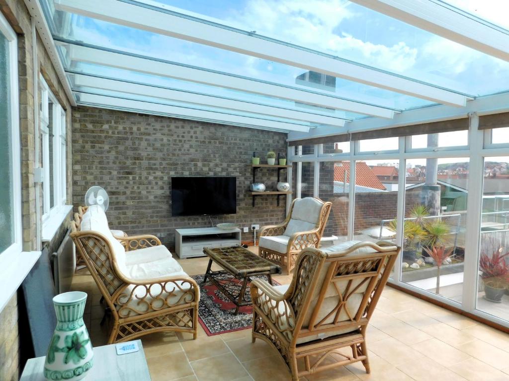 Sky View في شيرينغهام: حديقة شتوية مع غرفة معيشة مع كراسي ومدفأة