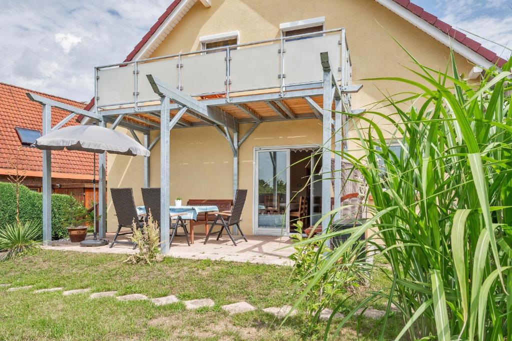 ein Haus mit einer Terrasse mit einem Tisch und einem Sonnenschirm in der Unterkunft Am Schulberg Ferienhaus Albatros in Heringsdorf