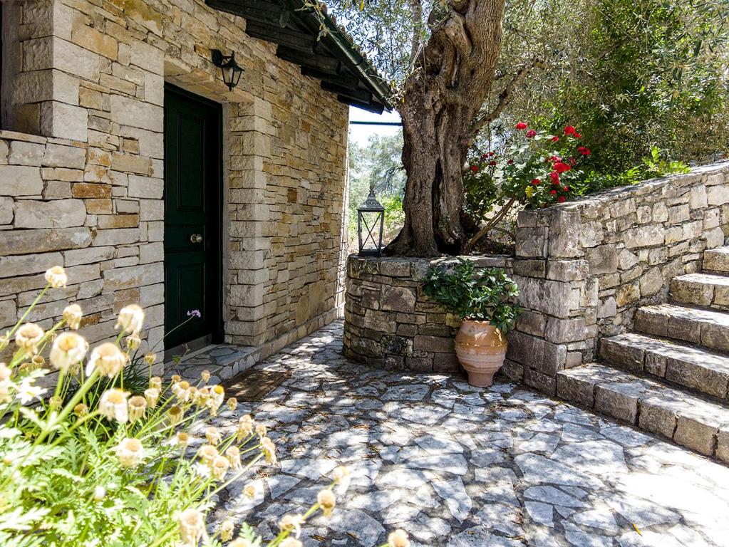 un edificio de ladrillo con una puerta negra y un árbol en Adamantia Traditional Village, en Bogdanátika