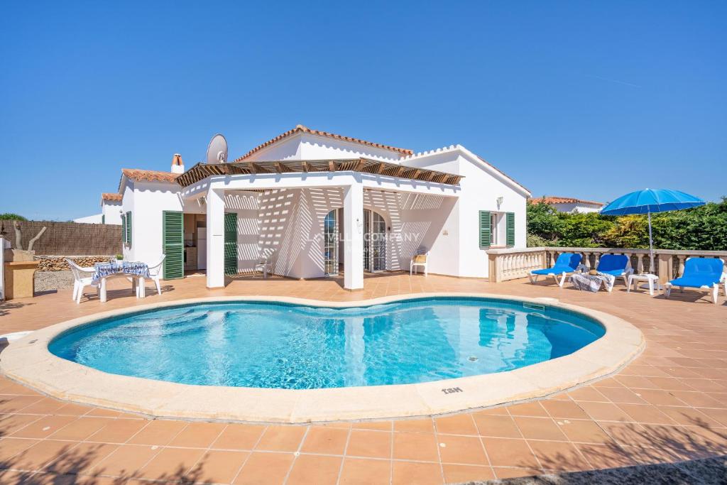 a swimming pool in front of a house at Villa CASSIA in Cala en Porter