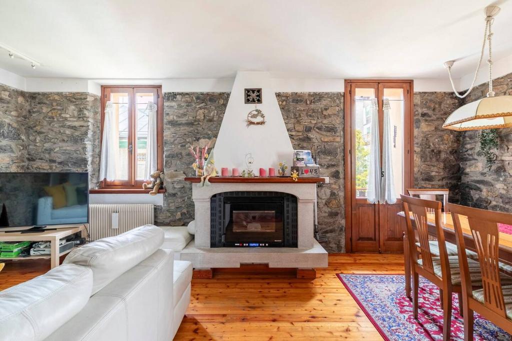 a living room with a white couch and a fireplace at The Family Stone House Holidays Apartaments Dolomiti Cortina in Venas