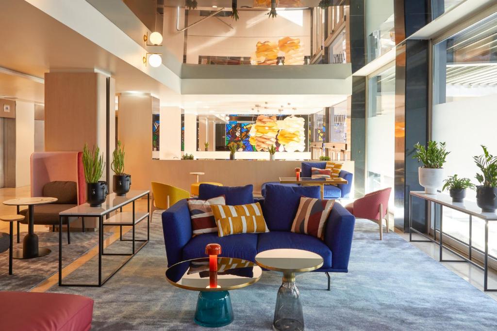 a lobby with a blue couch and chairs at voco Madrid Retiro, an IHG Hotel in Madrid