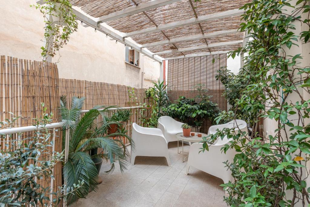 un patio avec des chaises blanches et des plantes dans un bâtiment dans l'établissement Sant'Agostino Apartment with Terrace by Wonderful Italy, à Palerme