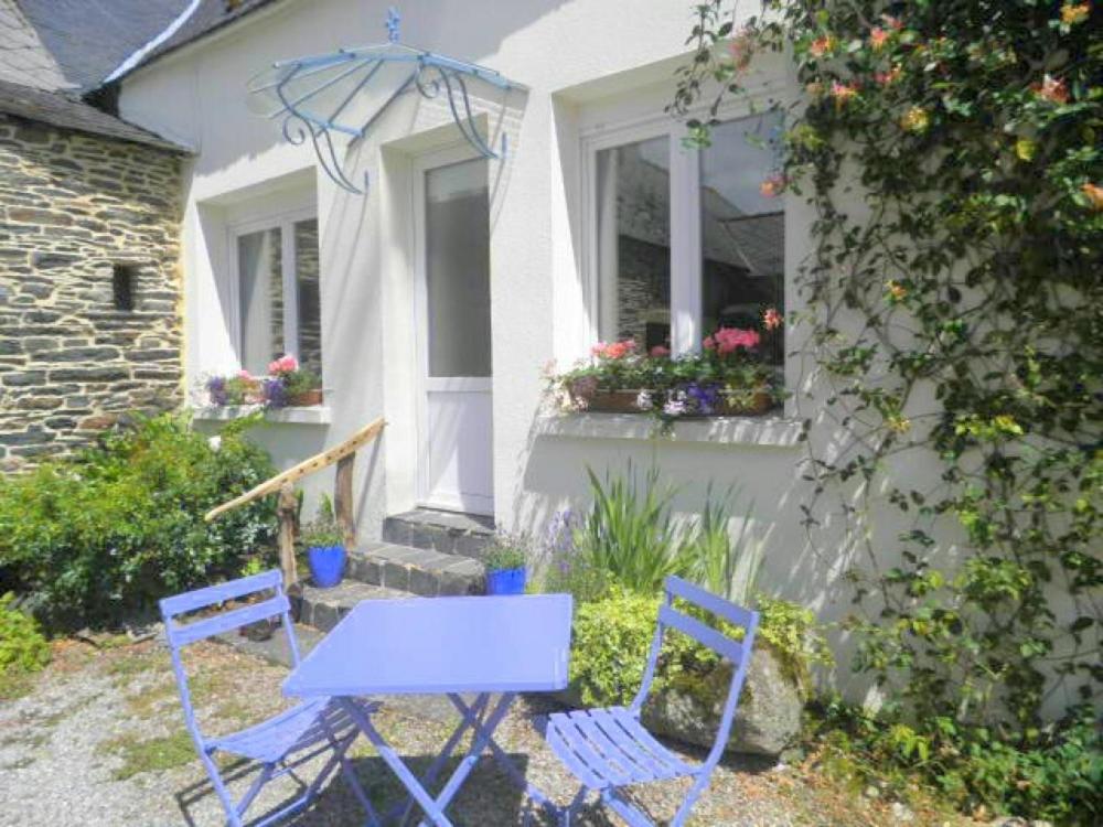 - deux chaises bleues et une table en face d'une maison dans l'établissement The Nightingales, à Laniscat