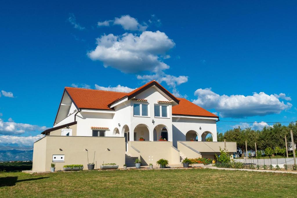 a large white house with an orange roof at Ema's Olive Garden Apt 1 with private parking, just 10 minutes drive from sandy beach in Poličnik