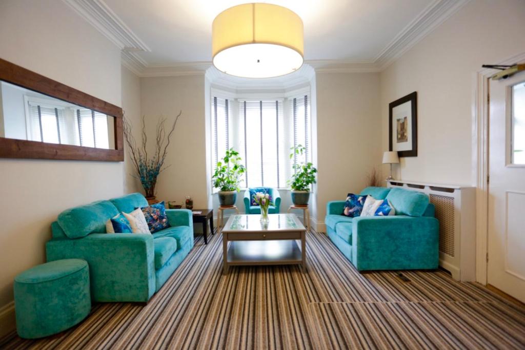 a living room with two blue couches and a table at The Dolphin Hotel Exmouth in Exmouth