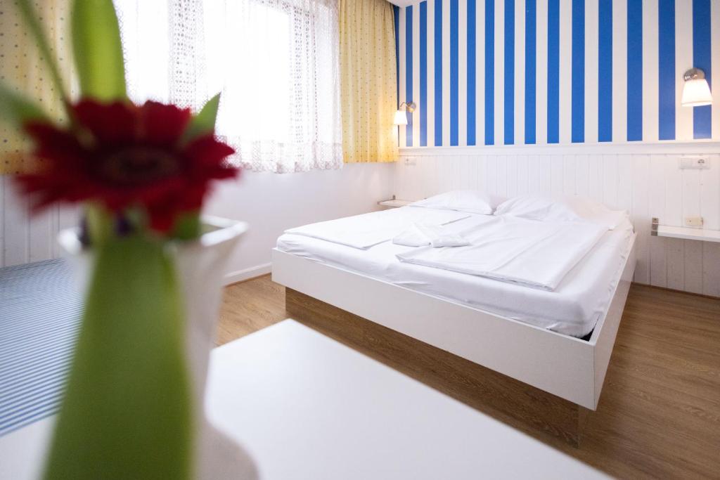 a bedroom with a bed and a vase with a flower at Pension Seerose in Pörtschach am Wörthersee