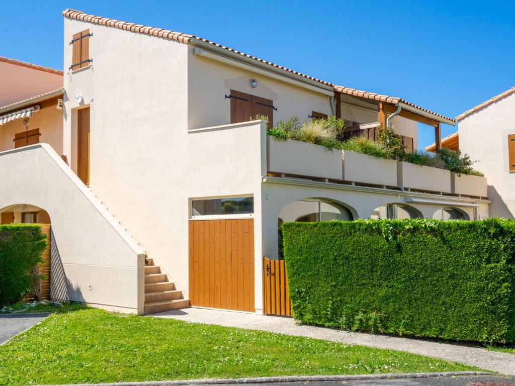 a white house with a gate and a hedge at Apartment Les Soleils Rouges-14 by Interhome in Vaux-sur-Mer