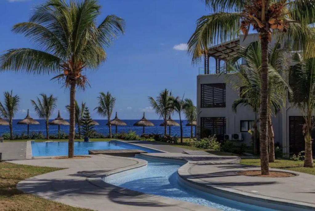 un complejo con piscina con palmeras y el océano en Oceanview 3-bedroom apartment, en Flic en Flac