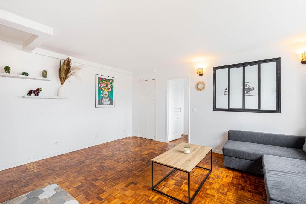 uma sala de estar com um sofá e uma mesa em 2 pièces, calme et lumineux. em Boulogne-Billancourt