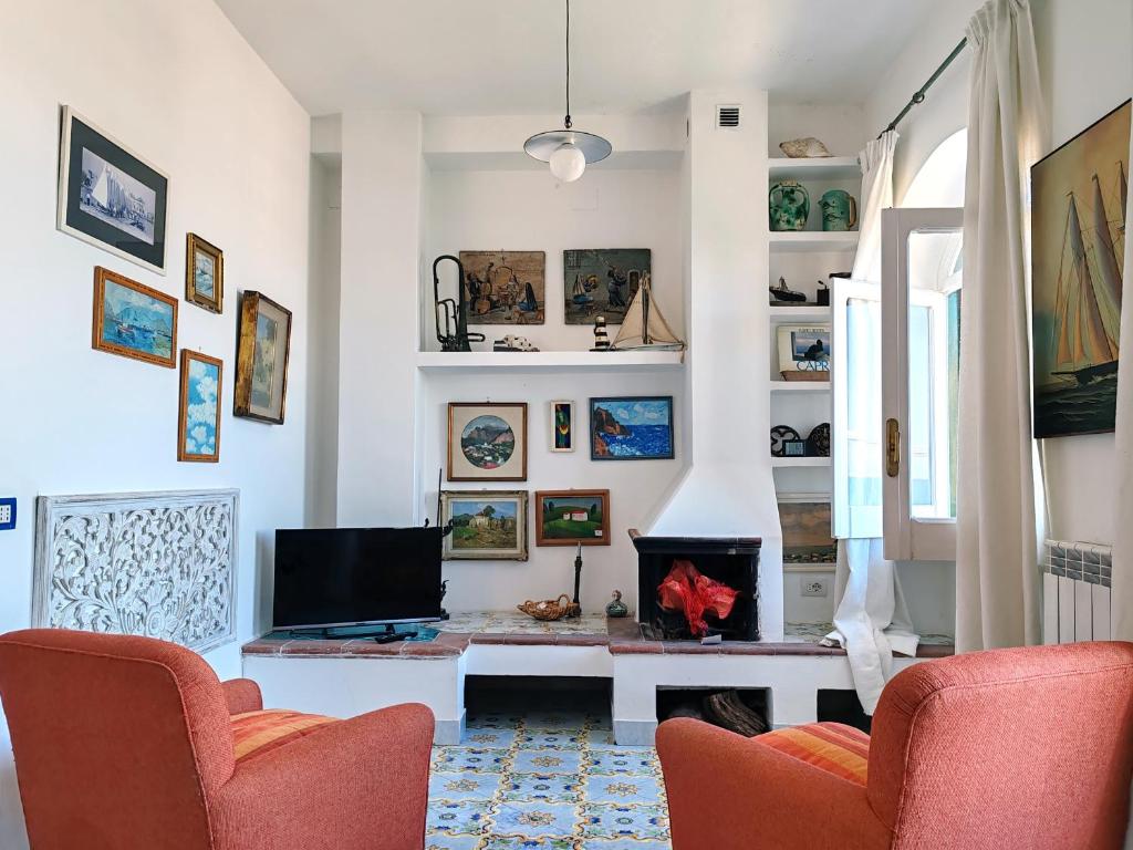ein Wohnzimmer mit einem Kamin und 2 Stühlen in der Unterkunft Mediterranea Casa del Capricorno in Massa Lubrense