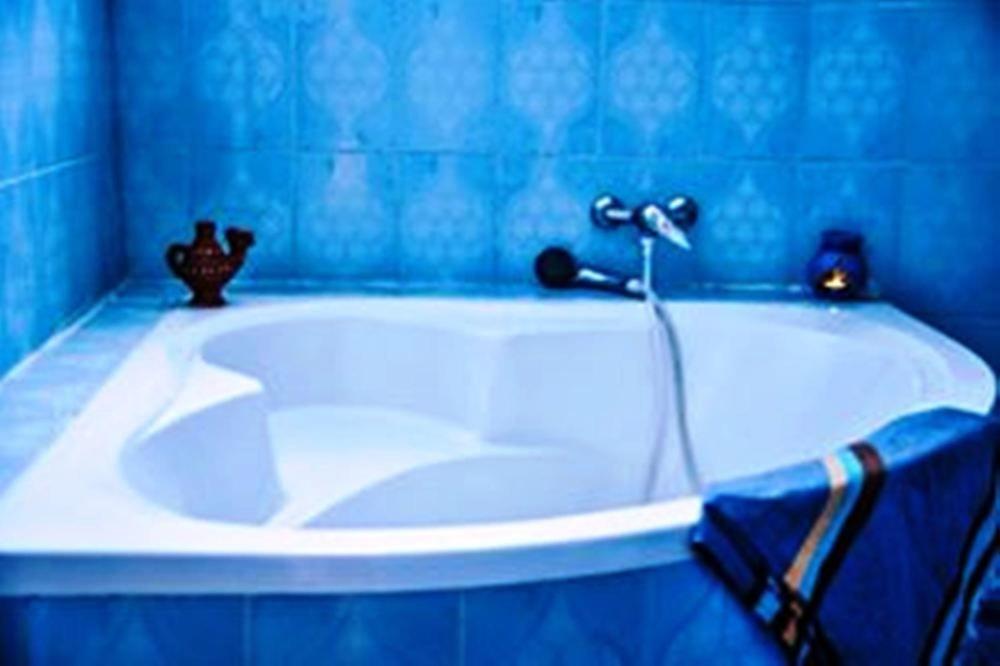 een blauwe badkamer met een wit bad met een kraan bij Love in Midoun