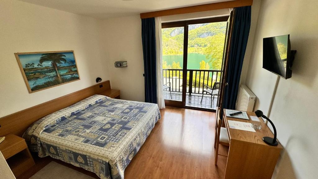een slaapkamer met een bed en een deur naar een balkon bij Albergo Stella Alpina in Tenno