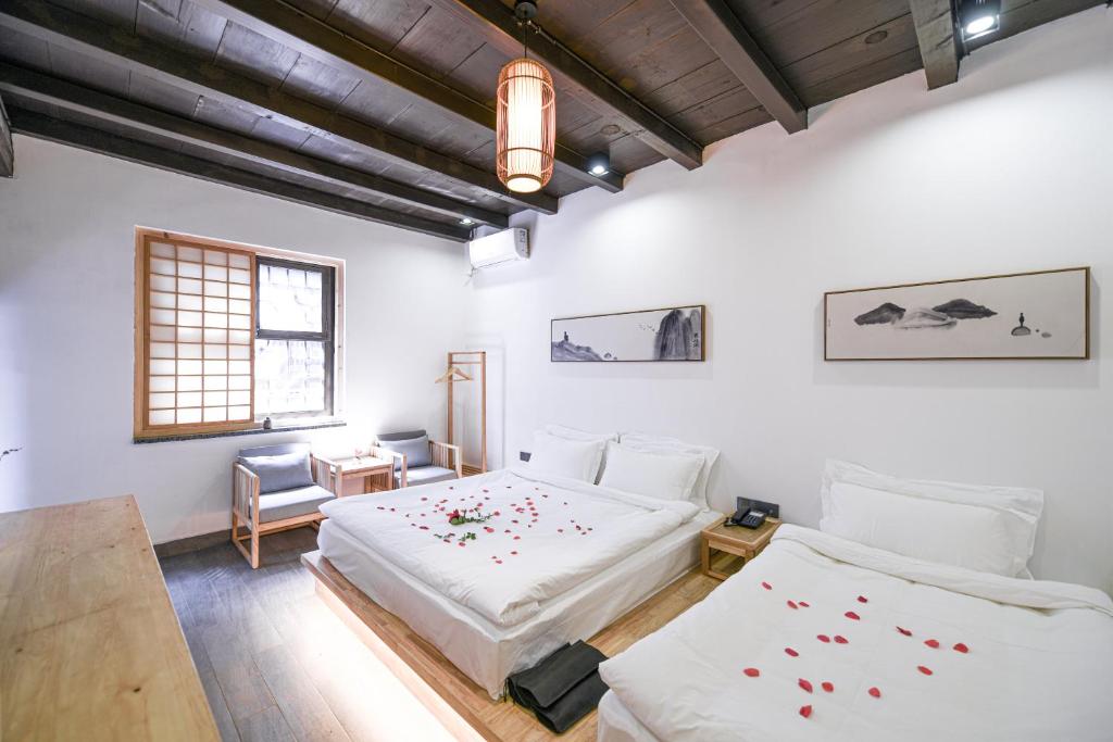 平遥県にあるElsewhere Xianya Hotelの白い壁の客室内のベッド2台