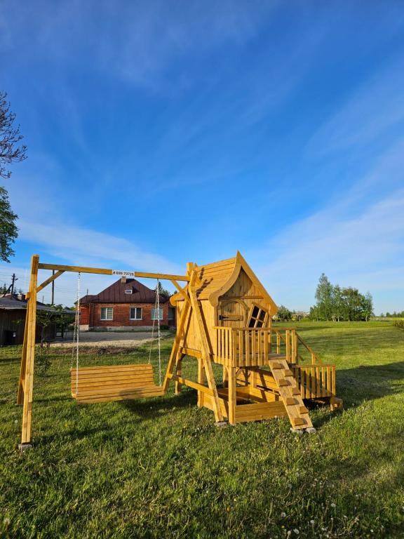 a wooden playground with a swing in a field at Red Brick House in Naciūnai