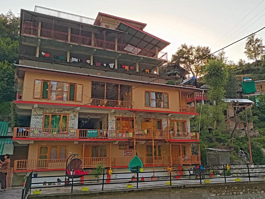 a large wooden building with balconies on a hill at Sharda Resort-Tirthan Valley in Banjār