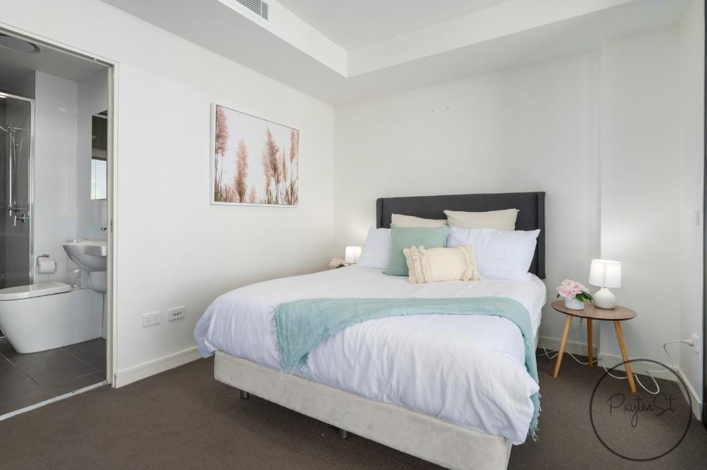um quarto branco com uma cama e uma casa de banho em Beachfront Beauty - Wifi Included em Newcastle