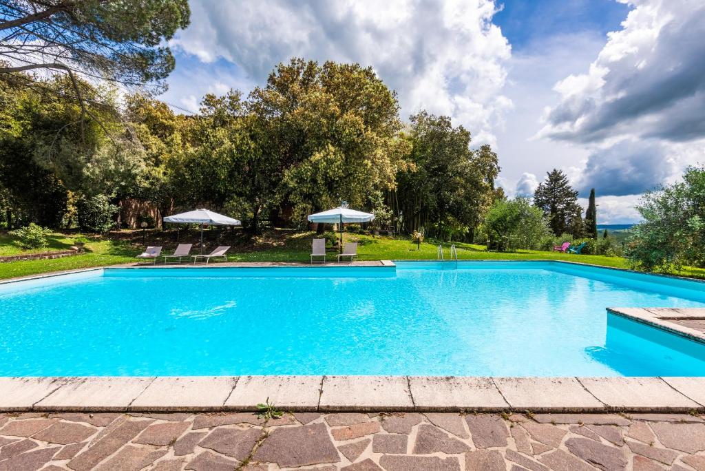 einen Pool mit Stühlen und Sonnenschirmen in der Unterkunft La Torre di Monsindoli in Siena