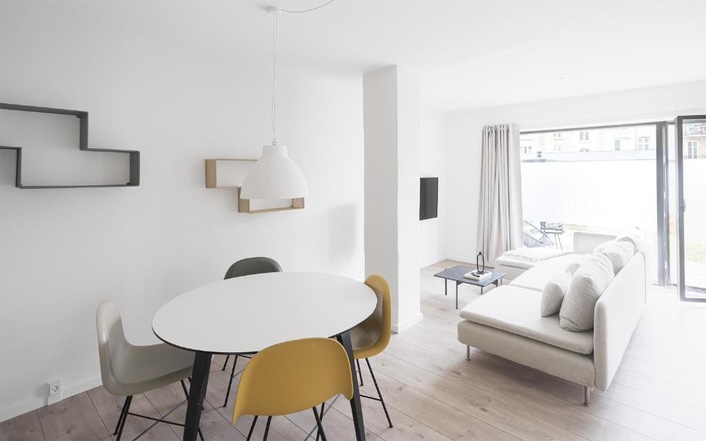 a white living room with a table and chairs at Fantastic 1-bed apartment w private terrace in Aarhus