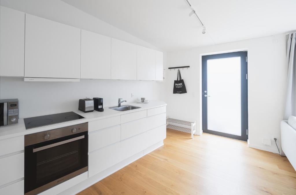 a white kitchen with a sink and a stove at Private Townhouse w terrace in Aarhus