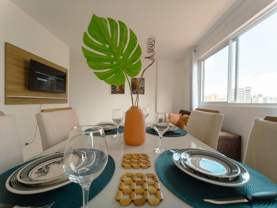 a dining room table with plates and glasses and a plant at Apto Centro Catedral RC1102 in Maringá