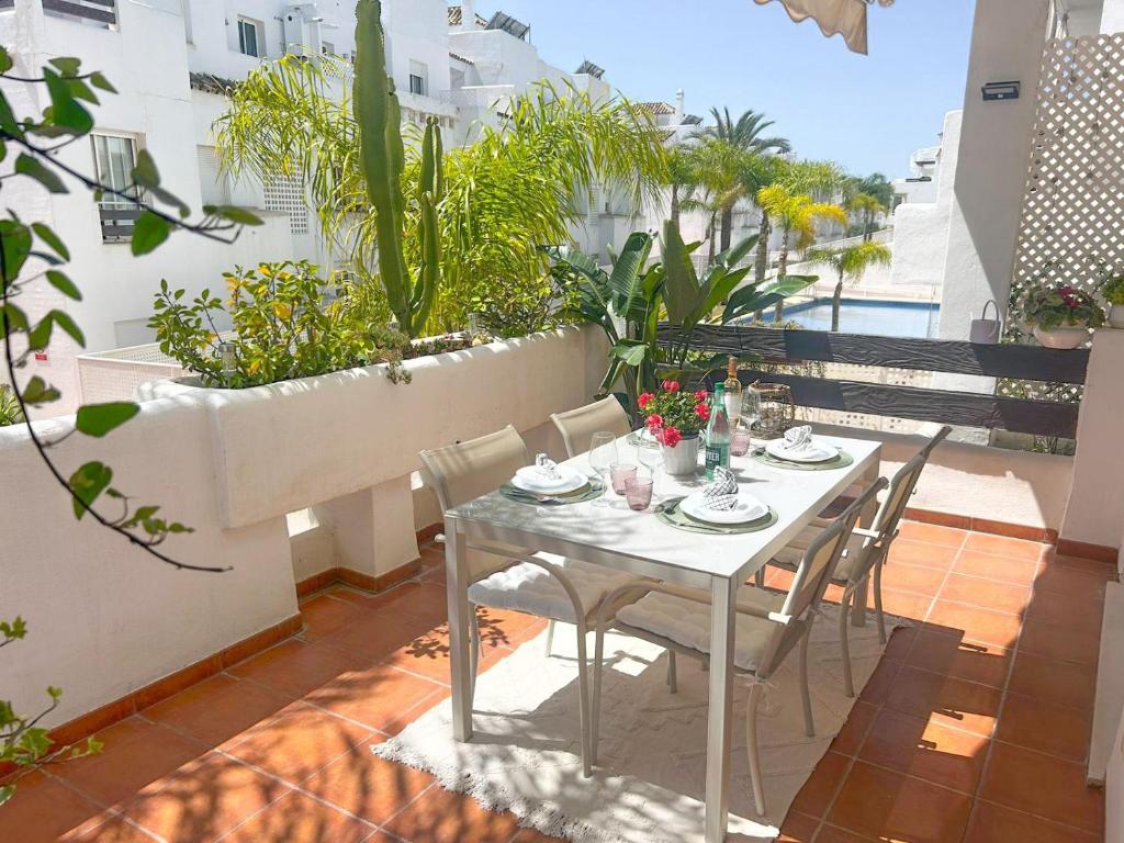 een tafel en stoelen op een balkon met planten bij Apartamento Golf Valle Romano in Estepona