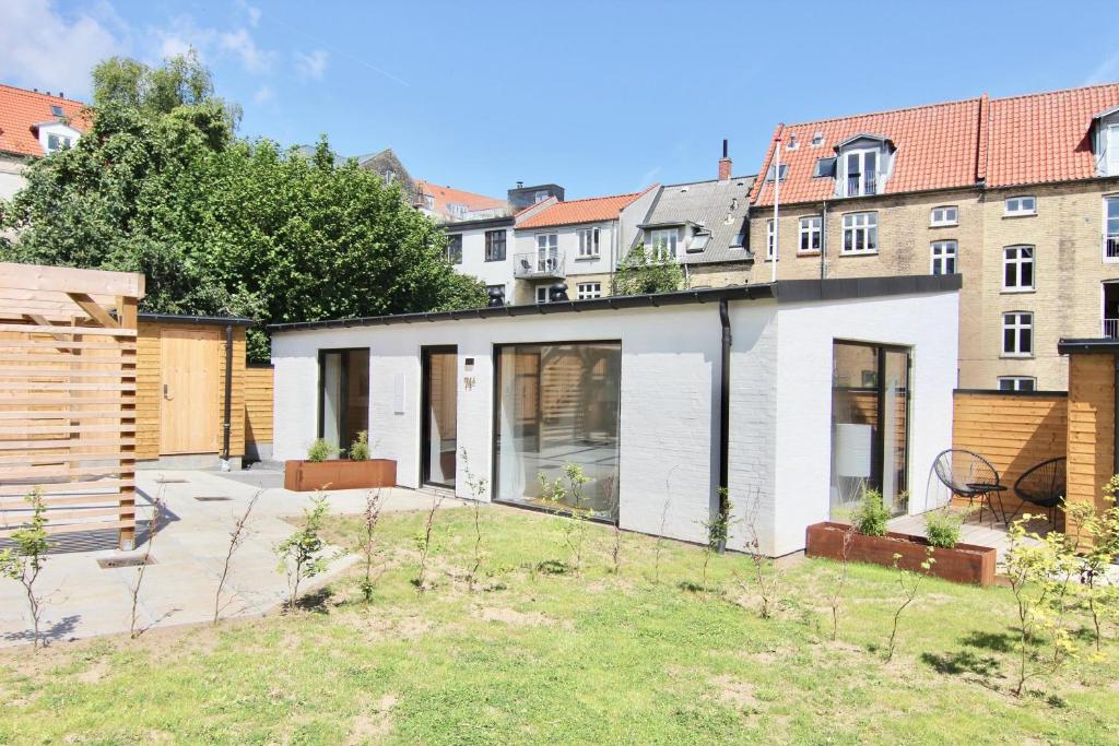 a white house with a garden and buildings at Private 1-bed townhouse w terraces in Aarhus