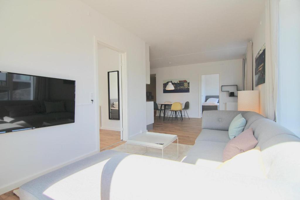 a white living room with a couch and a tv at Stunning 2-bed wbalconies and great views in Copenhagen