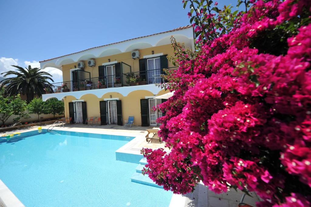 une villa avec une piscine et des fleurs roses dans l'établissement Marie Hotel, à Acharavi