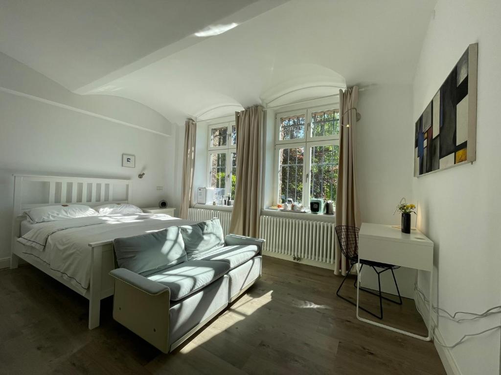 a white bedroom with a bed and a couch at Villa Krafft Bed&Breakfast in Waake