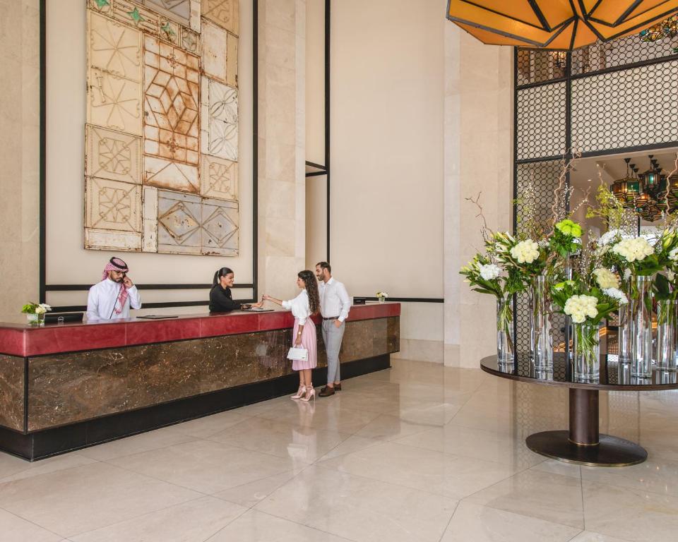 أصيلة أحد فنادق لاكشري كولكشن جدة في جدة: مجموعة من الناس تقف عند كونتر في بهو الفندق