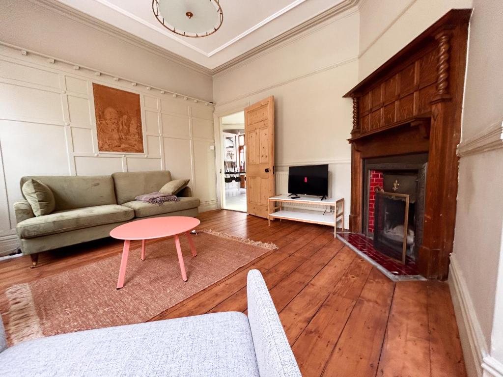 a living room with a couch and a table and a fireplace at Cardiff Victorian House Sleeps 6 in Roath 15mn City centre in Cardiff