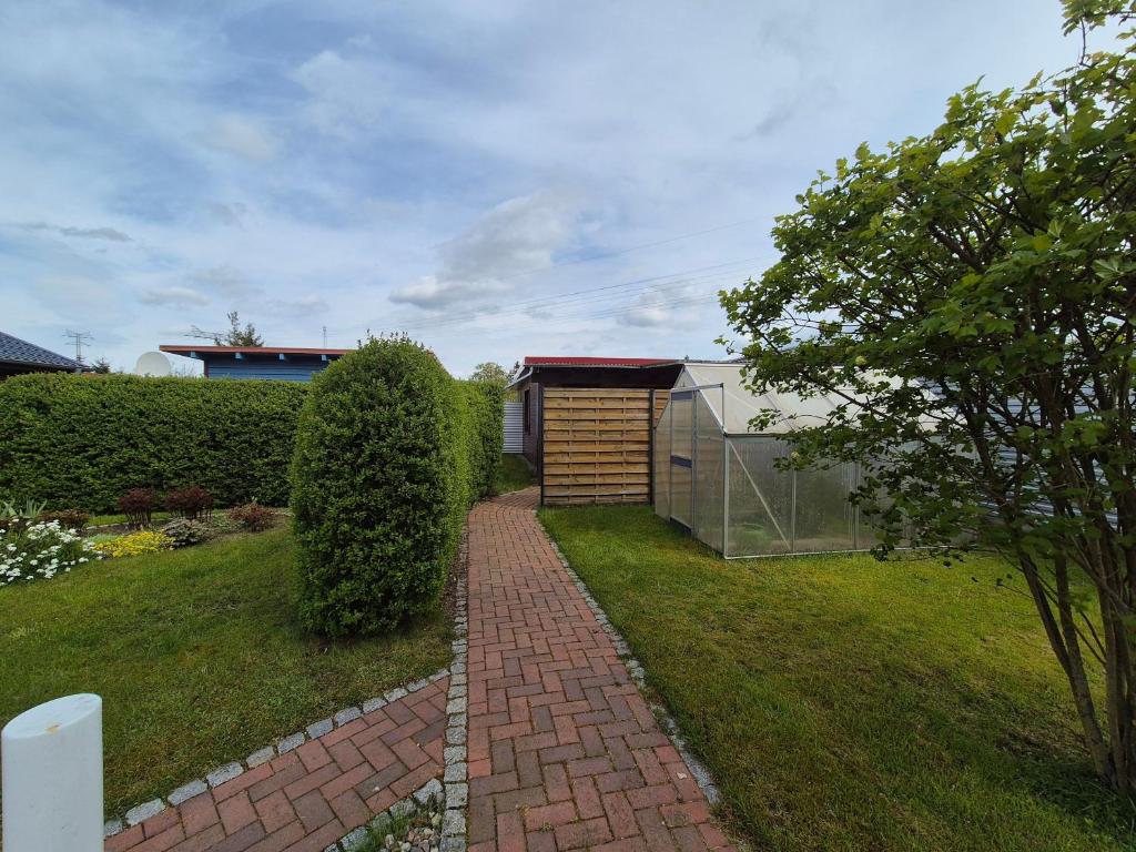 a garden with a brick walkway and a greenhouse at Eichholz-Hof kleines Ferienhaus Objekt-ID 15465-8 in Waren