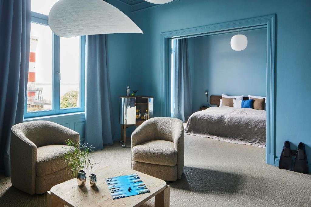 1 dormitorio con paredes azules, 1 cama y sillas en stilwerk Strandhotel Blankenese en Hamburgo
