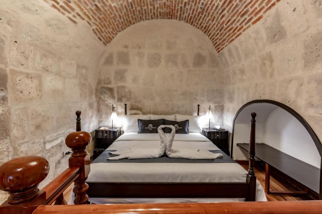 1 dormitorio con cama y pared de piedra en Casona Terrace Hotel, en Arequipa