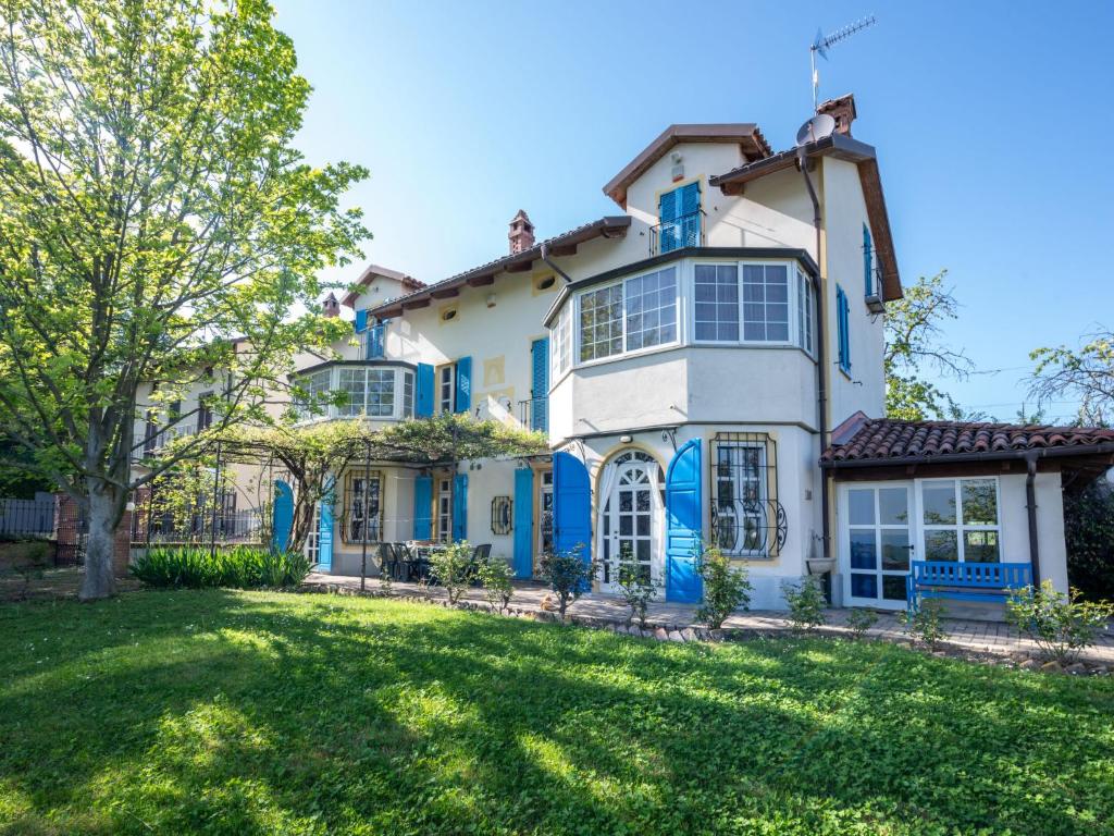 ein großes weißes Haus mit blauen Fenstern und einem Hof in der Unterkunft Holiday Home La Meridiana-1 by Interhome in San Damiano dʼAsti