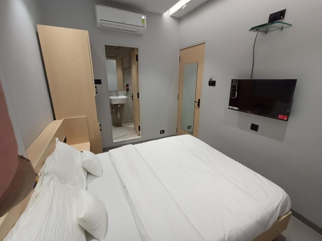 a bedroom with a white bed and a television at Hotel Golden Suites - Near Nesco in Mumbai