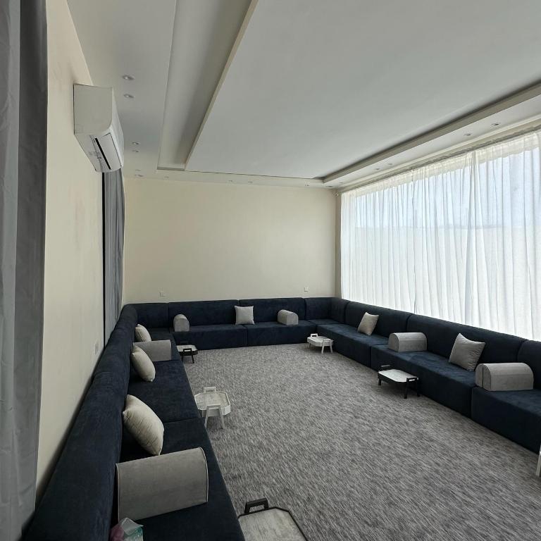 sala de estar con sofá azul y ventana grande en شاليهات حلم, en Al Aqiq