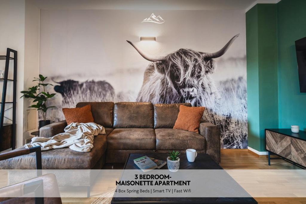 um sofá numa sala de estar com um mural de touro em ALPSTAY "Kuhstadl" - Maisonette, Gondelnähe & Netflix em Bad Kleinkirchheim