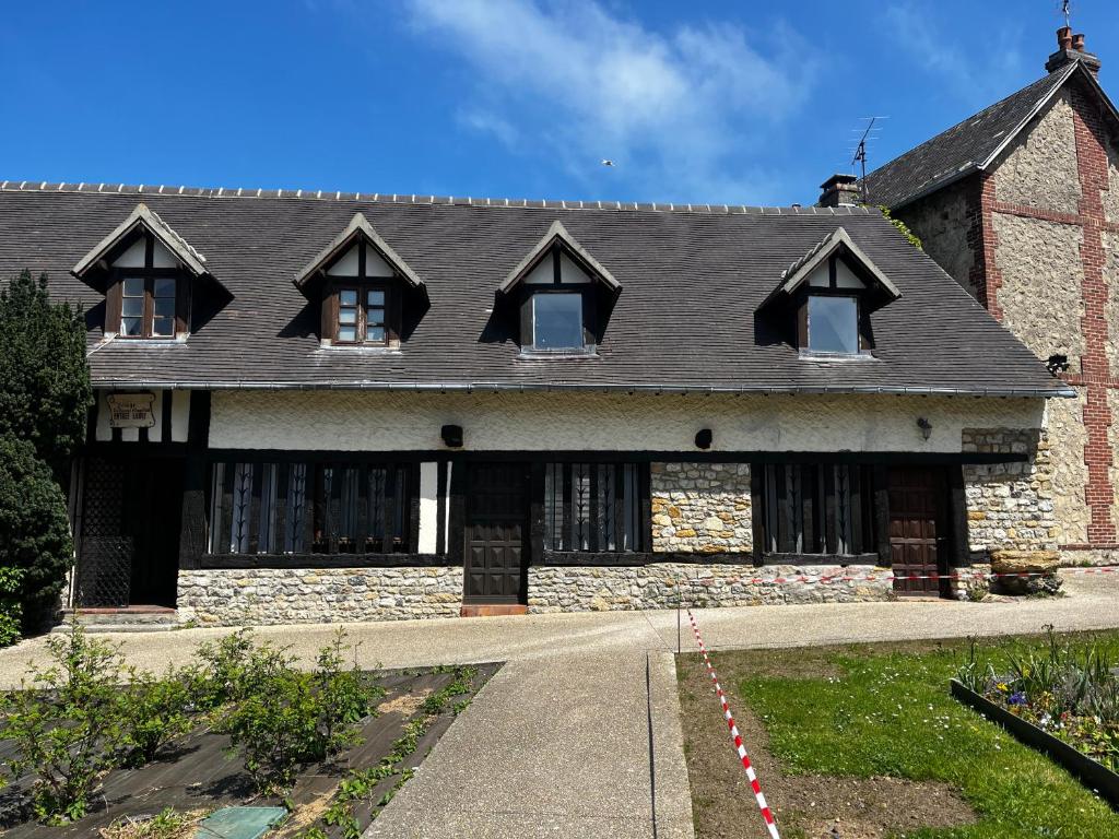 une maison en briques avec un toit noir et des fenêtres dans l'établissement Maison avec cheminée ancienne - Proche Cabourg, à Dives-sur-Mer
