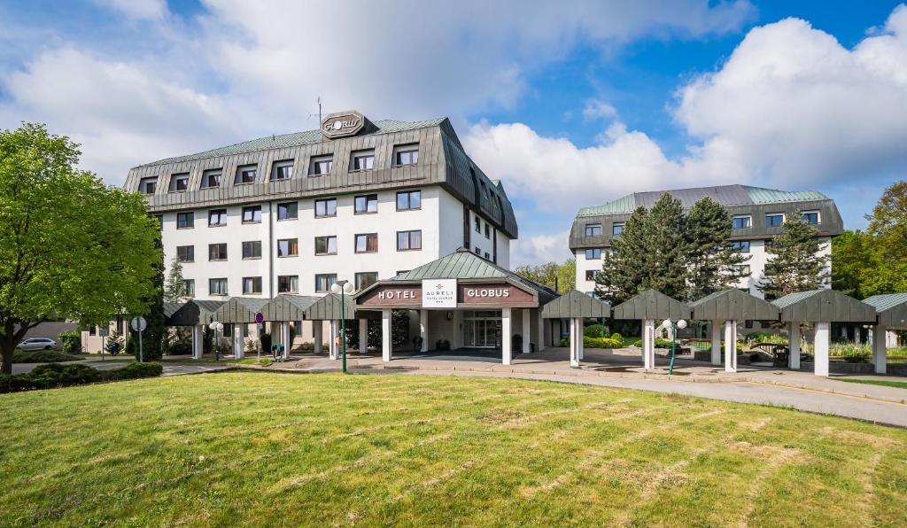 a large white building with a lawn in front of it at Hotel Globus in Prague